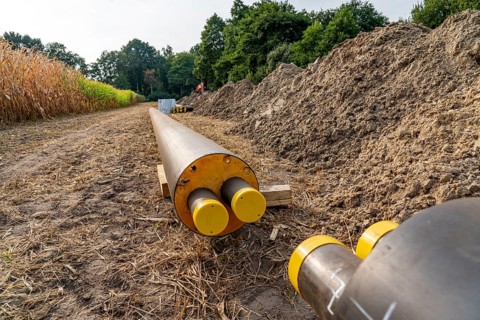 Laying of district heating pipes, next to a field, with maize, the district heating comes from a