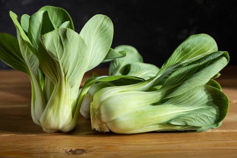 Fresh green bok choy or pac choi chinese cabbage on a gray wooden background. Hard light, contrast,