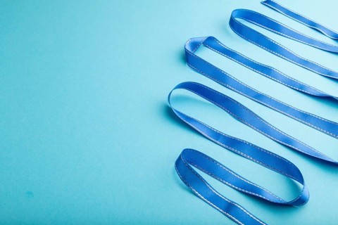 Blue ribbon on a blue pastel background. Celebration concept. Side view, copy space