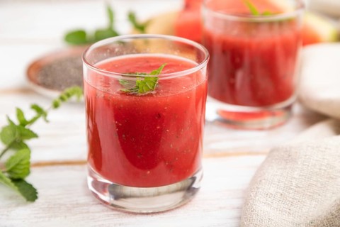 Watermelon juice with chia seeds and mint in glass on a white wooden background with linen textile.