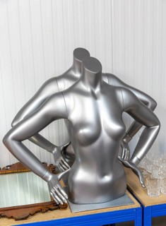 Two silver metallic faceless female mannequin torsos in auction room, UK
