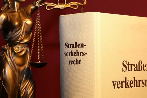 Symbolic image: Textbook on traffic law and a Justitia