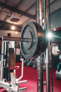 Dumbbell bar with weights on a machine in a fitness studio. In the background red floor, historic