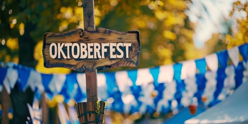 Banner with wooden sign with text 'Oktoberfest' at entry of traditional Bavarian German festival.