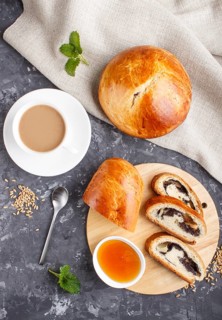 Homemade yeast buns and rolls with poppy seeds and honey on a black concrete background with a cup