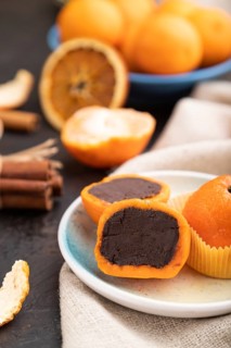 Truffle chocolate tangerine candies on a black concrete background and linen textile. Side view,