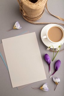 Gray paper sheet mockup with spring snowdrop crocus and galanthus flowers and cup of coffee on gray