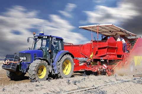 Tractor with harvester harvesting potatoes