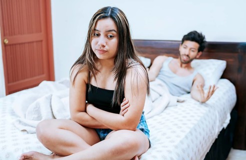 Wife arguing with her husband in bed. Young couple arguing sitting on the bed. Upset woman with