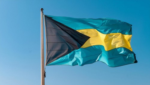The flag of the Bahamas flutters in the wind, isolated against a blue sky