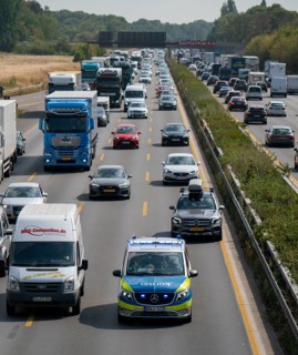 Police patrol car with flashing blue lights and siren working its way through a traffic jam on the