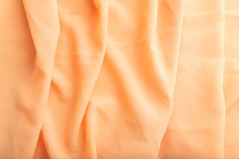 Fragment of orange linen tissue. Top view, natural textile background and texture. wave concept,