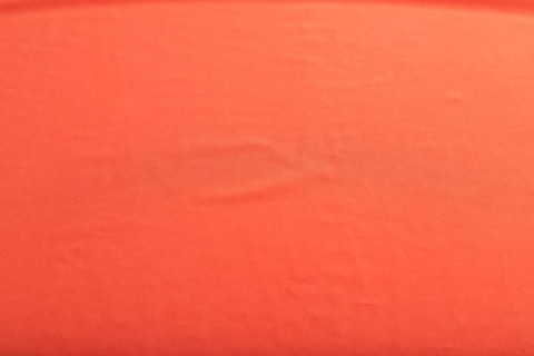 Fragment of smooth red silk tissue. Top view, flat lay, natural textile background and texture
