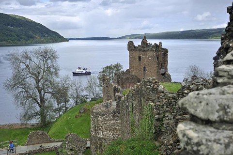 Cruise boat on Loch Ness in front of the ruins of Urquhart Castle near Drumnadrochit, Scotland, UK