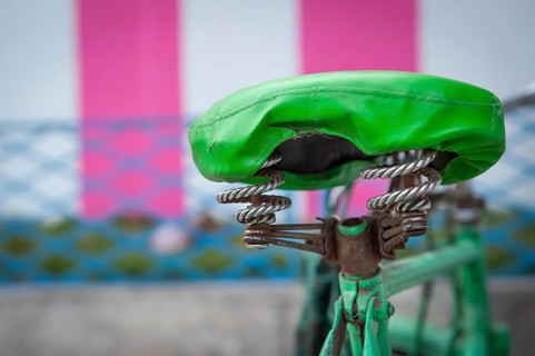 Green bicycle saddle, green bicycle in front of white-pink coloured temple outer wall, Tamil Nadu,