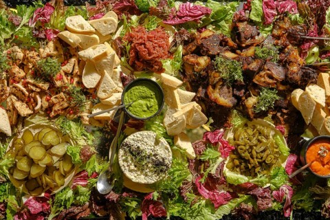 An elaborate arrangement of Mediterranean dishes showcases grilled meats, fresh vegetables,