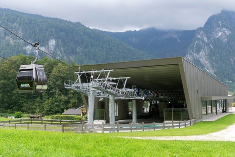 Cable car of the Jennerbahn at the valley station, surrounded by green meadows and wooded mountains