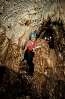 Young woman with helmet and headlamp, tourist between stalactites and stalagmites in a stalactite