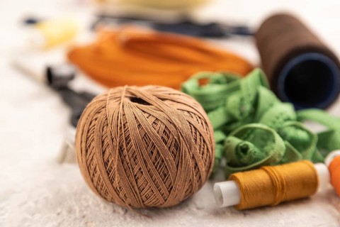 Sewing accessories: scissors, thread, thimbles, braid on gray concrete background. Side view, close