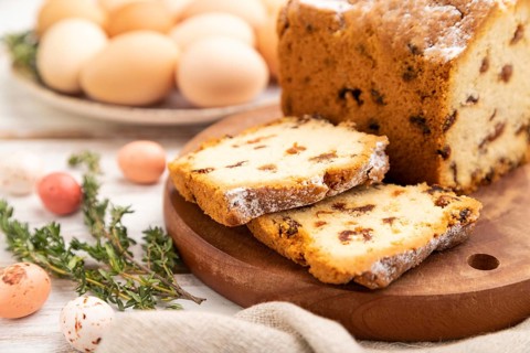 Homemade easter pie with raisins and eggs on plate on a white wooden background and linen textile.