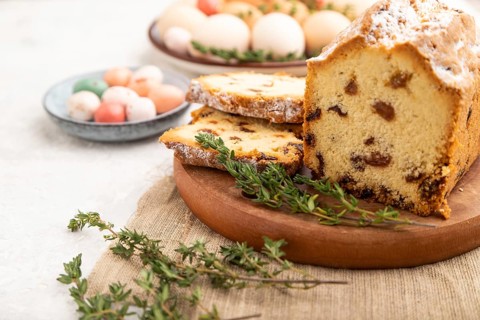 Homemade easter pie with raisins and eggs on plate on a gray concrete background and linen textile.