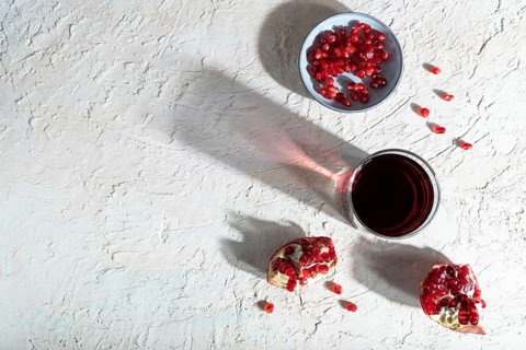 Glass of pomegranate juice on a white concrete background. Hard light, contrast. Top view, copy