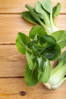 Fresh green bok choy or pac choi chinese cabbage on a brown wooden background. Top view, close up,