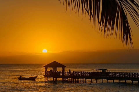 Atmospheric sunset with a boat near a busy jetty, Dominicus beach, Bayahibe, Dominican Republic,