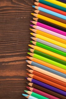 Set of watercolor pencils on brown wooden background. Top view, flat lay, close up