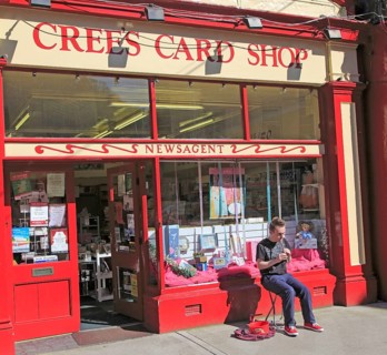 Boy busking playing tin whistle outside shop, Youghal, County Cork, Ireland, Irish Republic, Europe