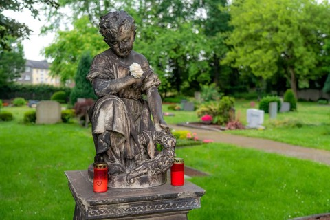 Figure in a cemetery, old gravestone, with flower and grave light, North Rhine-Westphalia, Germany,