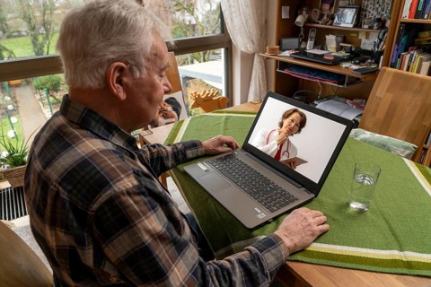 Symbolic image of telemedicine, elderly patient speaking to a doctor in a video conference from