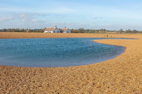 Lagoon of water used by swimmers on beach at Shingle Street, Suffolk, England, UK