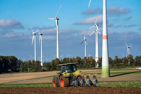 Farmer working in the fields, with a tractor, wind farm above the village of Lichtenau,