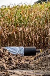Laying of district heating pipes, next to a field, with maize, the district heating comes from a