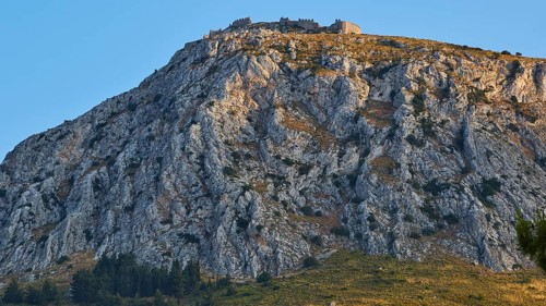 The golden hour illuminates a mountain with an ancient castle at the top, Archaic Castle,