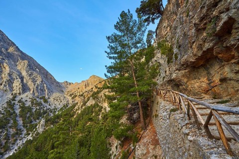 Stony hiking trail along a rock face, surrounded by mountains and trees, Xyloskalo, wooden
