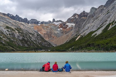 Hikers sitting on the shore of the glacial lake Laguna Esmeralda, Tierra del Fuego Island,