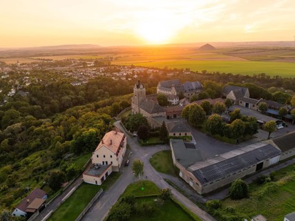 Aerial view of a castle in the warm light of sunset, surrounded by houses and fields, Allstedt,