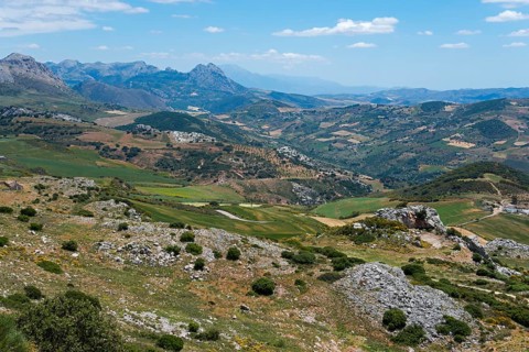 Extensive mountain landscape with valleys and green areas under a cloudy sky, view from the nature