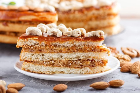 Piece of homemade cake with caramel cream and nuts on a gray concrete background. side view, close