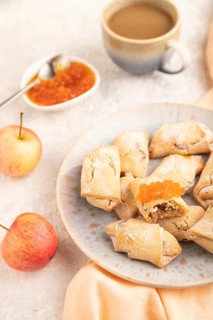 Homemade sweet cookie with apple jam and cup of coffee on gray concrete background and orange linen