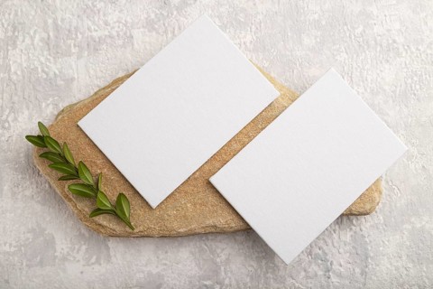 White paper business card, mockup with natural stone and boxwood branch on gray concrete background