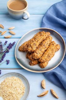 Crumble cookies with seasme and almonds on ceramic plate with cup of coffee and blue linen textile
