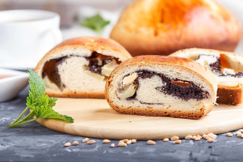 Homemade yeast rolls with poppy seeds and honey on a wooden kitchen board on a black concrete