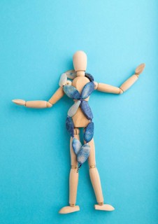 Wooden mannequin with blue agate beads on blue pastel background. copy space, isolated, luxury, bad