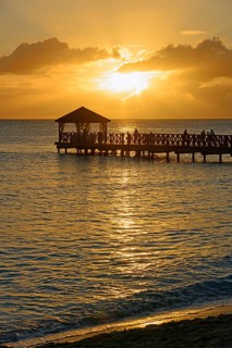 People on a jetty watching the sunset over the sea with beautiful reflection on the water,