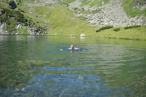 Hiker swimming in the ice-cold mountain lake Mittlerer Kaltenbachsee, Sölktäler Nature Park,
