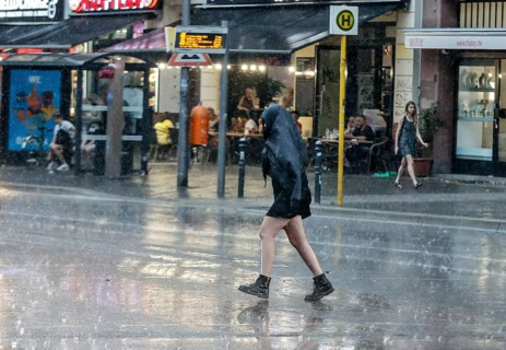 People run across Potsdamer Strasse in heavy rain. After weeks of heat, the first heavy rain