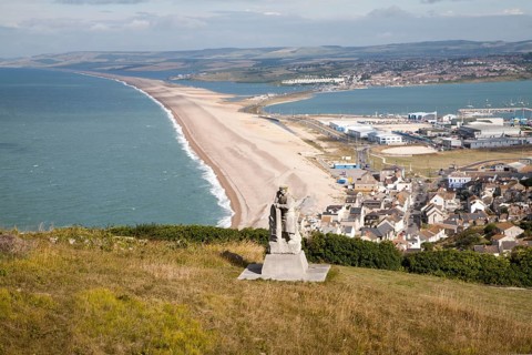 Chesil beach tombolo, with quarrying monument in the foreground Chiswell, Isle of Portland, Dorset,